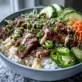 A close-up of the Korean Beef Power Bowl, featuring juicy marinated beef, crisp cucumbers, and spicy jalapeño slices on rice.