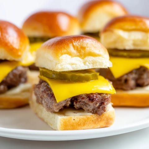Freshly grilled mini hamburgers topped with melted cheddar, perfect for a slider feast.