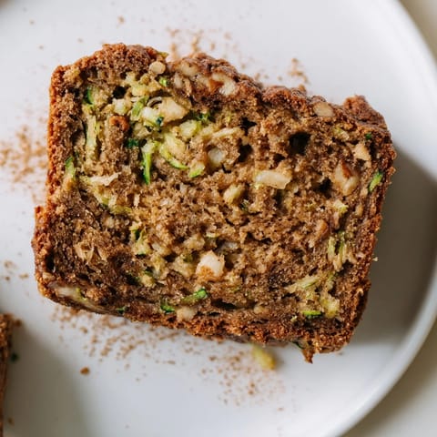 Warm, spiced zucchini bread, studded with walnuts, offering a delicious scent of home baking.
