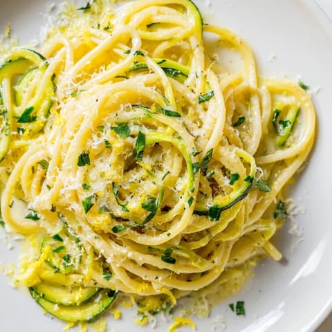 A skillet of fresh Lemon Zucchini Pasta with parsley and Parmesan, garnished with extra cheese and red pepper flakes.