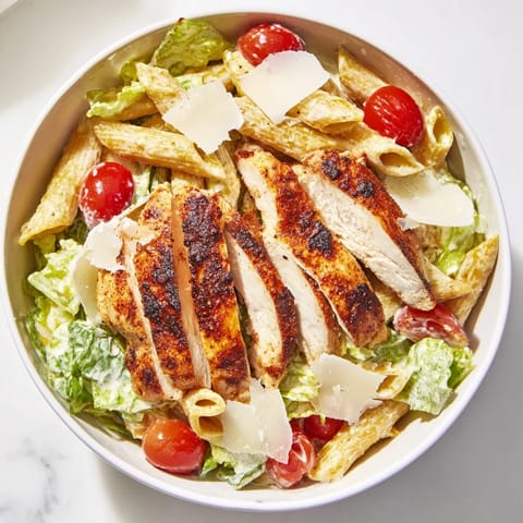 A vibrant bowl of Spicy Chicken Caesar Pasta topped with shaved parmesan and croutons, ready to serve for dinner.