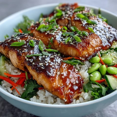 Flaky Asian-Inspired Salmon Bowl topped with sesame seeds, served on fluffy rice with crisp vegetables and a lime wedge.
