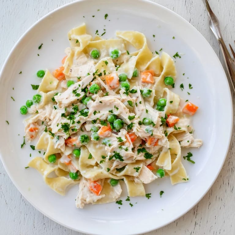In this one-pan Spring Chicken Noodle Skillet, al dente pasta, vibrant spring vegetables, and savory chicken are coated in a velvety Parmesan sauce under a garnish of parsley.