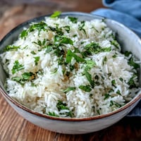 Freshly steamed Cilantro Lime Rice garnished with chopped cilantro and a lime wedge on a rustic plate.